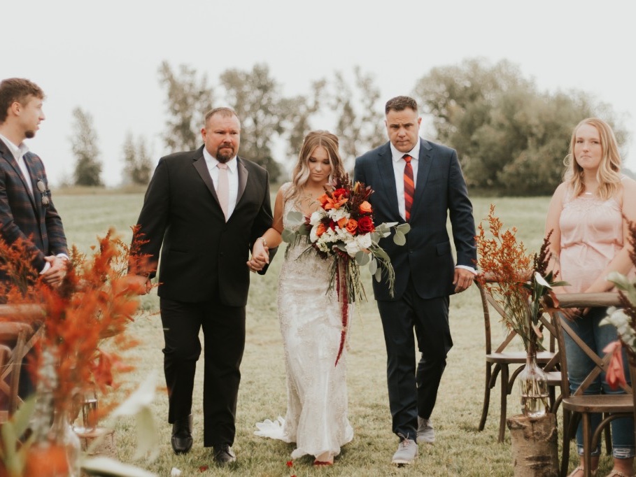 Bride walking the grove aisle with her parents